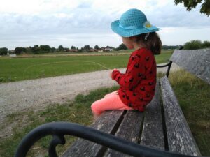 Kind mit blauem Hut auf Bank
